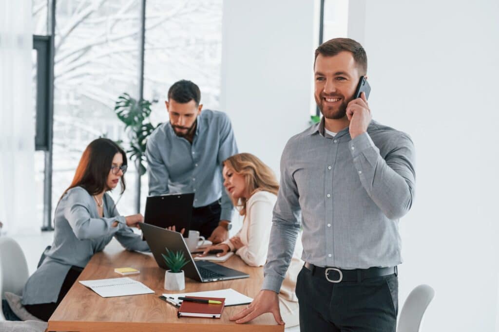 Man with phone. Group of business people that working on the project in the office